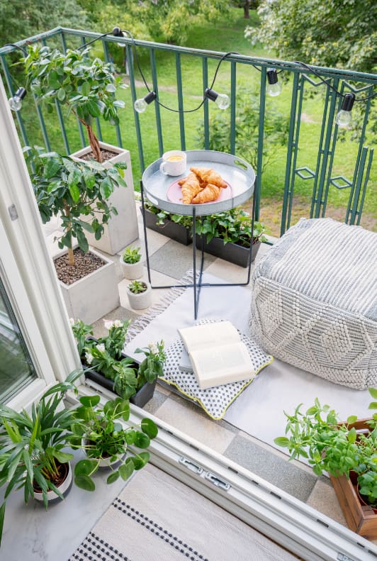 Malý balkon s rostlinami, stolkem a pufem
