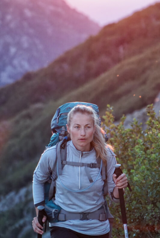 Woman with grey t-shirt and outdoor backpack walking in the mountains