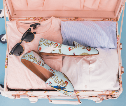 Otevřený růžový palubní kufr s oblečením a botami